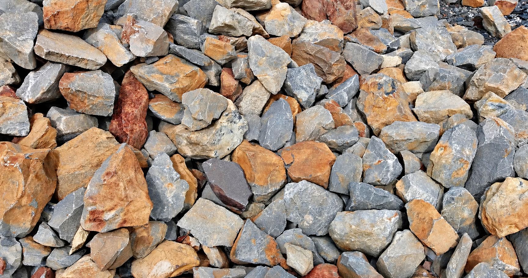Gros plan sur un tas de blocs de roche anguleux aux teintes grises et ocre, empilés les uns sur les autres.